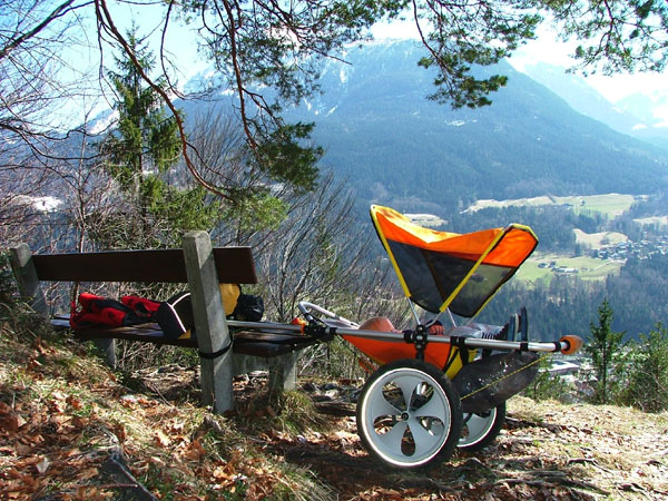 gogo kid mit schlafendem kind an eine bank agebunden, mit blick auf berge inden alpen